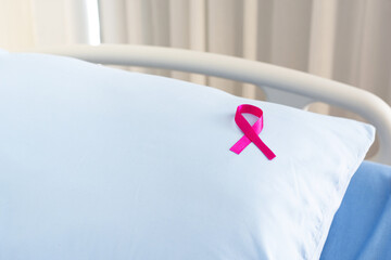 Pink Ribbon on blue pillow on hospital bed. The ribbon sign represents breast cancer awareness.