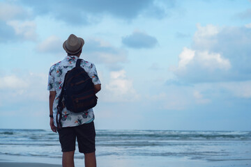 Young man standing at the coast looking at view at dawn