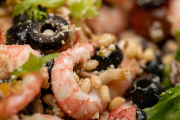 Vegetable salad with prawns and pine nuts on a plate. Homemade food. Close up.