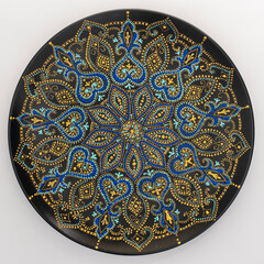 Decorative ceramic plate with black, blue and golden colors, painted plate on background , dot painting