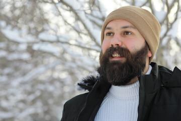 Bearded man in the winter woods. Attractive happy young man with beard walk in the park.