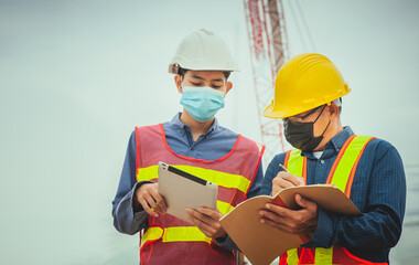 Two worker working on site construction with tablet technology and using mask prevention covid19 coronavirus