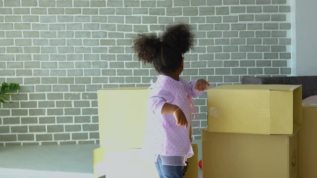 Happy cute active little African American girl fun to playing by fighting to carton box in living room and she look happiness for playing in her home