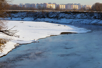 Landscape of a cold autumn river with snow outside the city.