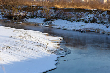 Landscape of a cold autumn river with snow outside the city.