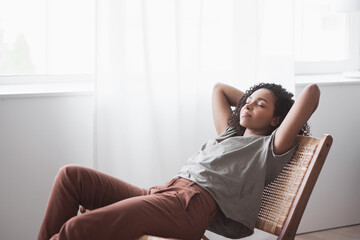Young woman relaxing at home. African american girl resting in her room. Enjoy life, rest, relaxation, wellbeing, lifestyle, people, recreation concept - Powered by Adobe