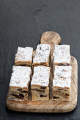 Christmas stollen slices with cranberry on black stone background