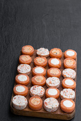 Smoked salmon assorted canapes on wooden board on black stone background