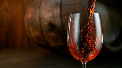Detail Shot of Pouring Red Wine from Bottle with Old Barrel Wooden Background