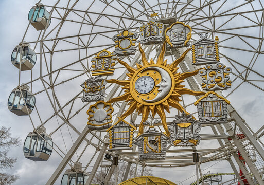 Ferris wheel with clock. musical clocks with various decorations are built into the wheel mechanism. the photo was taken against a gray cloudy sky on an autumn day
