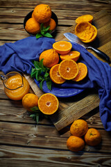 fresh orange juice and oranges with mint on the table with blue cloth and knife 