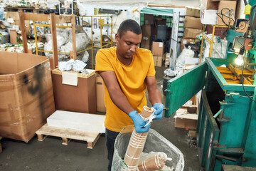 Man unpacking disposable cups into compressing machine
