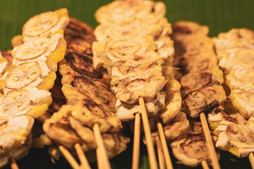 Food concept. Grilled fruit snacks on wooden stick in Thailand fresh food market. Image with shallow depth of field