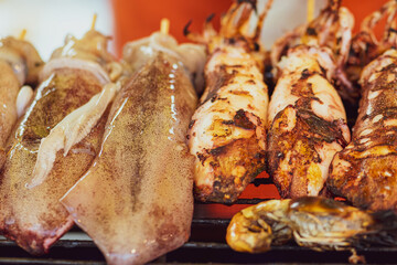 Food concept. Squids making on grill in Thailand fresh food market. Image with shallow depth of field