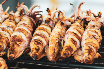 Food concept. Squids with lemon slices making on grill in Thailand fresh food market. Image with shallow depth of field