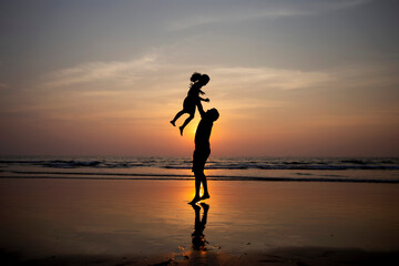 Bringing back good memories.

Silhouette of father and daughter playing on beach during sunset. 