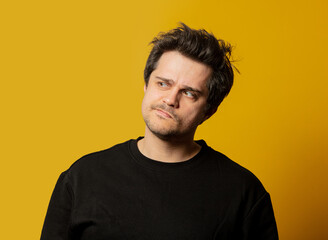 Obraz premium Surprised white guy in black shirt on yellow background