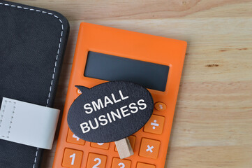 Top view of notebook, calculator and wooden tag written with text SMALL BUSINESS. 