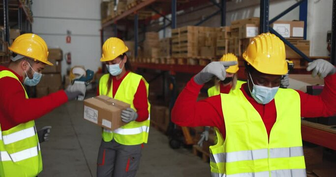 Happy workers dancing inside warehouse while wearing safety masks during coronavirus outbreak - Industrial and delivery concept