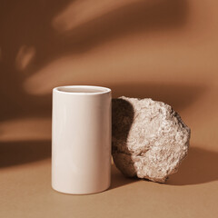 Beige stone and grey glass podium on a beige background, natural background with shadow of tropical plant for your product