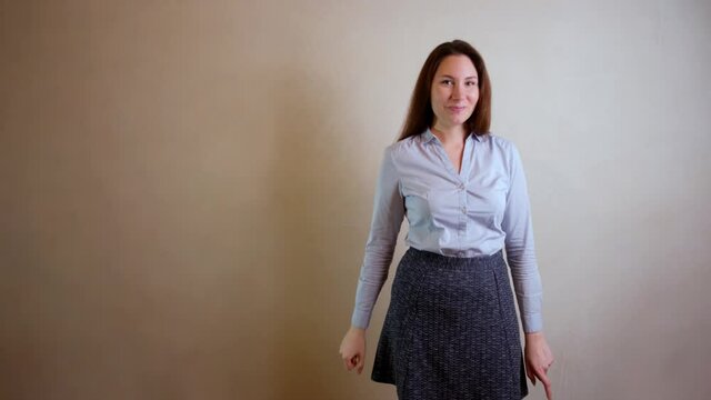 Concept of the idea. A beautiful brunette girl in a blue shirt against a gray wall raises her finger up and nods her head affirmatively. Gesture, emotion