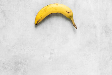 Peeled banana on a grey concrete background