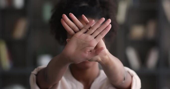 African woman raising folded palms to camera makes defensive hands gesture close up. Female struggle against domestic violence and abuse, social issues, citizen position, against vaccination concept