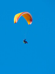 Paraglider flying in blue sky.
