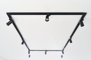 Modern LED black track spot lights in the interior. Hanging lamps spotlights attached to a concrete...