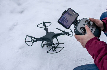 The operator controls the drone using a remote control and a mobile phone.