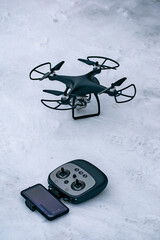 Black quadrocopter with camera on snow terra in countryside.