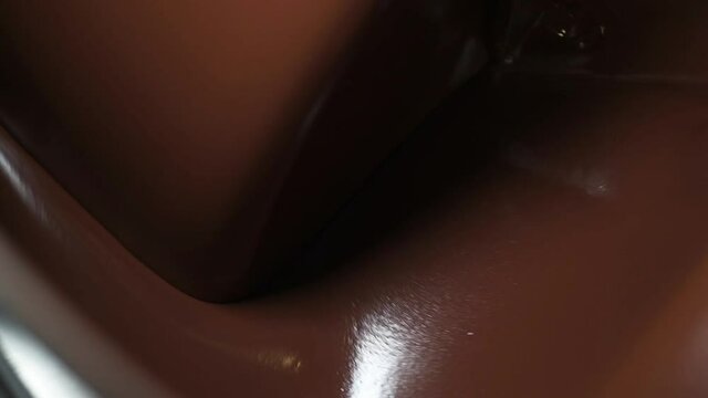 Liquid melted chocolate inside a chocolate conching machine. The machine grind the chocolate to smooth paste with friction and heat.