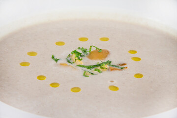 Creamy mushroom soup with herbs on a white plate and a blue background