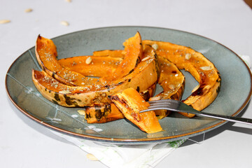 Baked pumpkin slices, sprinkled with dried herbs, drizzled with olive oil.