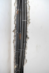 Heating pipes with polyethylene foam insulation are installed in a concrete wall. Vertical photo
