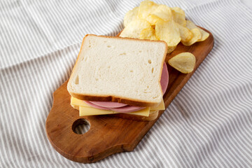 Homemade Bologna and Cheese Sandwich on a rustic wooden board on cloth, low angle view.