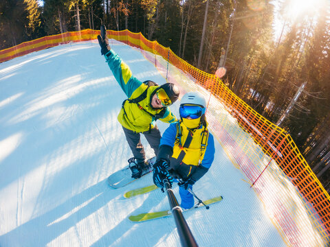 couple snowboarder and skier taking selfie at ski slope