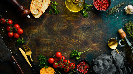 Fototapeta na wymiar Food background: spices, vegetables and cutlery on a dark table. Free space for your text.