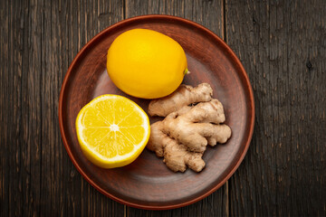 Top view ginger and lemon in a plate on a wooden background as ingredients for lemonade detox