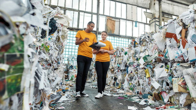 Man with woman going between piles of waste paper