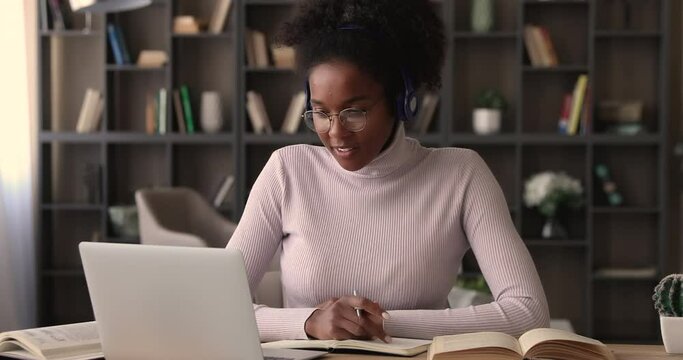 Diligent african student listen audio online course on laptop through headphones enjoy interesting remote study. University admission educational webinar, internet resources for self-education concept