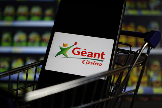 Viersen, Germany - May 9. 2020: Close up of mobile phone screen in shopping cart modell with logo lettering of french geant casino supermarket chain (focus on center of logo)