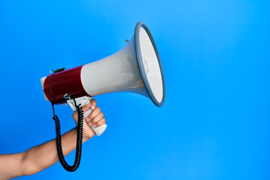 Hand of hispanic man holding megaphone over isolated blue background.