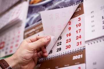 Male hand turns the pages of a calendar 2021 close-up.