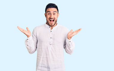 Fototapeta premium Young handsome man wearing casual clothes celebrating victory with happy smile and winner expression with raised hands
