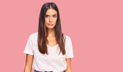 Obraz premium Young hispanic woman wearing casual white tshirt skeptic and nervous, frowning upset because of problem. negative person.