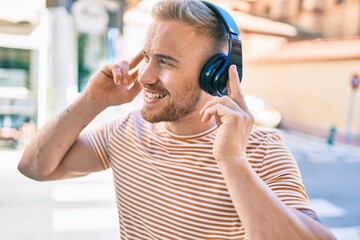 Young irish man smiling happy listening to music using headphones at street of city.