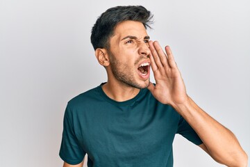 Young handsome man wearing casual clothes shouting and screaming loud to side with hand on mouth. communication concept.