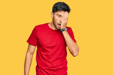 Young handsome man wearing casual red tshirt yawning tired covering half face, eye and mouth with hand. face hurts in pain.