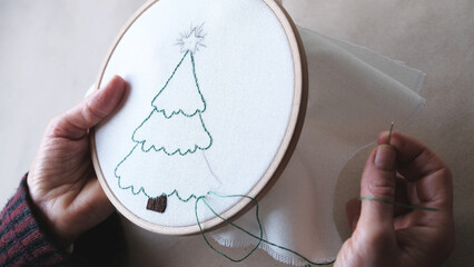 Embroidery.Woman hands holding embroidery hoop and needle.Brown background. © yasin